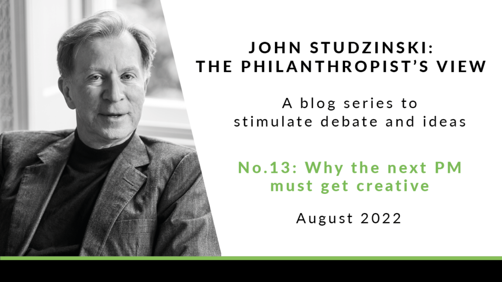 To the left is a black and white headshot of John Studzinski, wearing a grey jacket, and white high neck jumper underneath. He has short grey hair, and is looking to the side. To the right of the image is a white background with black text saying 'John Studzinski - Philanthropist's View. A blog series to stimulate debate and ideas. No. 13: Why the next PM must get creative. August 2022'.